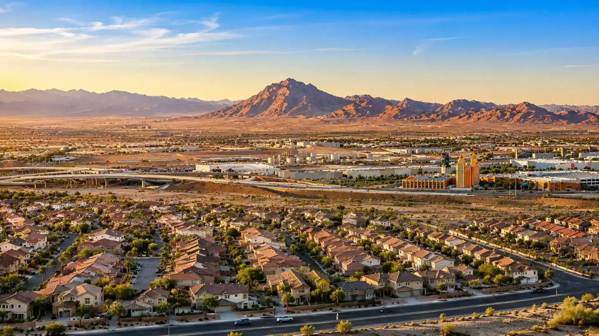 Aerial view of suburban neighborhood with mountains in the background at sunset.